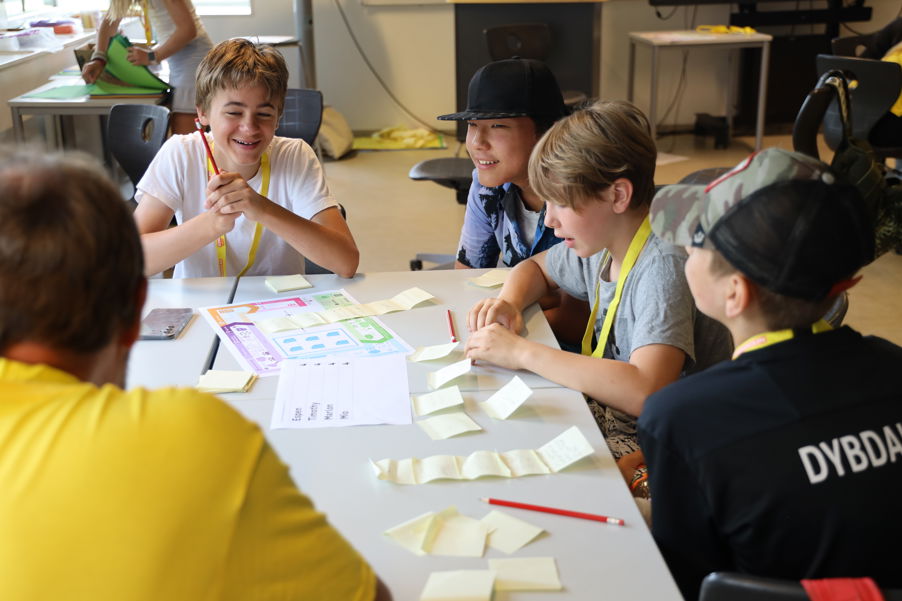 en gruppe mennesker som sitter ved et bord med papirer og penner