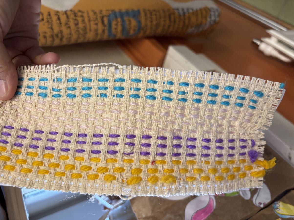 en hånd som holder et fargerikt firkantet objekt